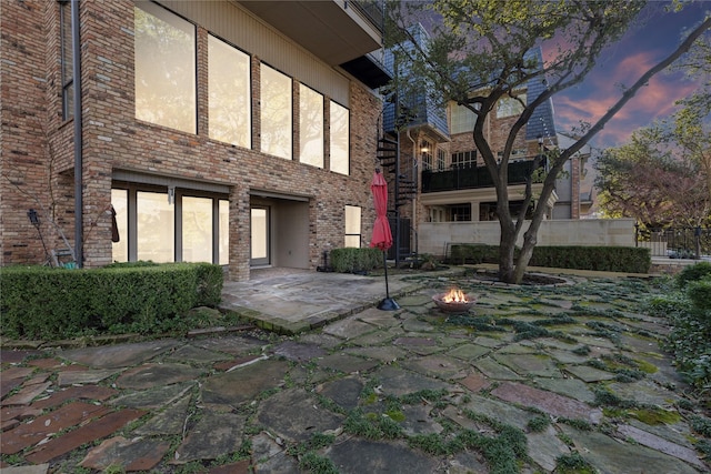 back house at dusk with a fire pit and a patio