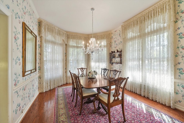 dining room with wood-type flooring, a notable chandelier, and crown molding