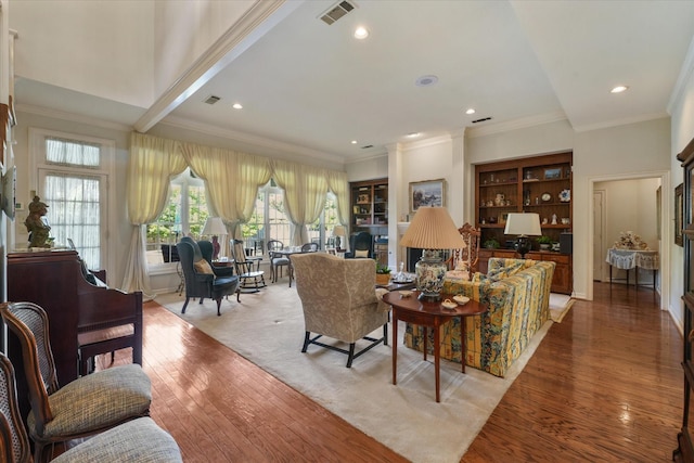 living room with built in shelves, ornamental molding, and light wood-type flooring