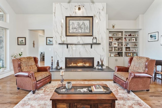 living room with hardwood / wood-style floors, built in features, and a fireplace