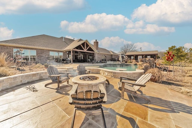 view of swimming pool with a fire pit and a patio area