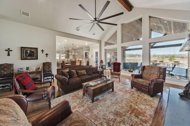 living room featuring hardwood / wood-style flooring, ceiling fan with notable chandelier, lofted ceiling with beams, and a healthy amount of sunlight