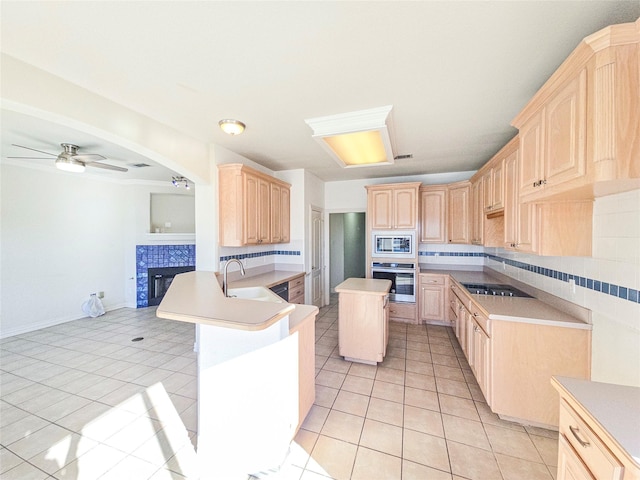 kitchen with light tile patterned flooring, light brown cabinetry, a center island, kitchen peninsula, and stainless steel appliances