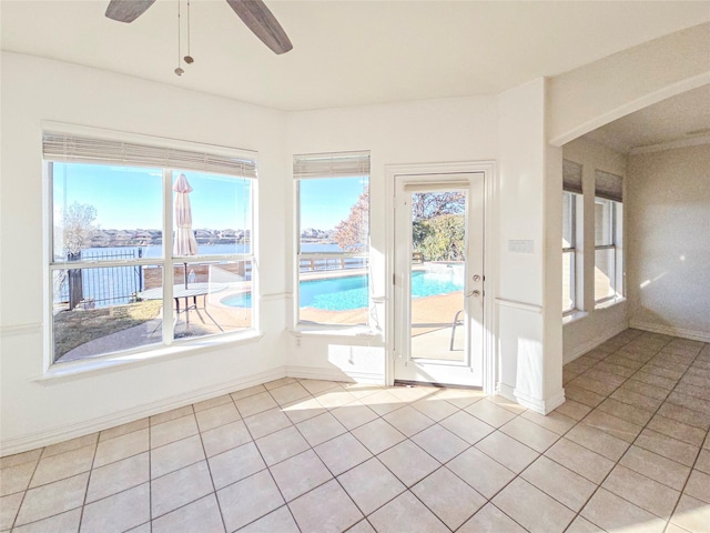 tiled spare room featuring a water view, a healthy amount of sunlight, and ceiling fan