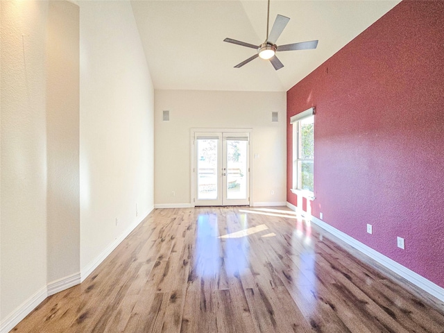 unfurnished room featuring high vaulted ceiling, french doors, ceiling fan, and light wood-type flooring