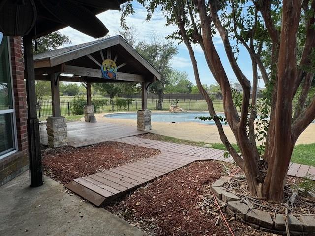 surrounding community with a pool, fence, a gazebo, and a patio area