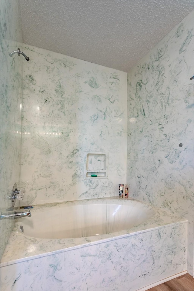 bathroom featuring hardwood / wood-style flooring, a textured ceiling, and a tub to relax in