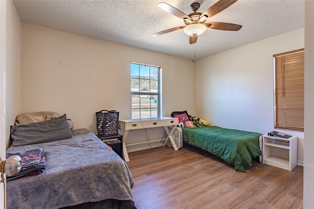 bedroom with ceiling fan, a textured ceiling, and light hardwood / wood-style flooring