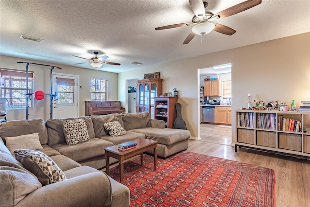 living room with ceiling fan, sink, light hardwood / wood-style floors, and a textured ceiling