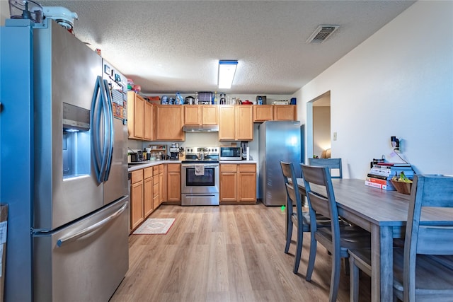 kitchen featuring appliances with stainless steel finishes, a textured ceiling, and light wood-type flooring