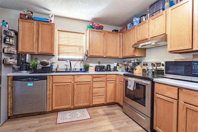 kitchen featuring sink, stainless steel appliances, a textured ceiling, and light wood-type flooring