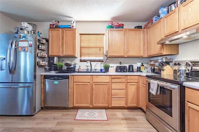 kitchen featuring sink, appliances with stainless steel finishes, light hardwood / wood-style floors, a textured ceiling, and light brown cabinets