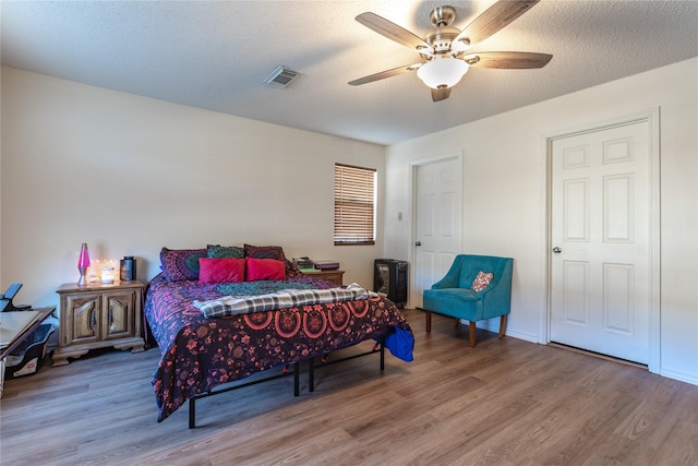 bedroom with hardwood / wood-style flooring, a textured ceiling, and ceiling fan