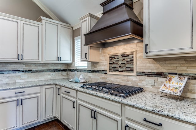 kitchen with white cabinets, decorative backsplash, custom exhaust hood, stainless steel gas cooktop, and light stone counters