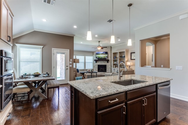 kitchen featuring a fireplace, sink, a kitchen island with sink, stainless steel dishwasher, and dark brown cabinets