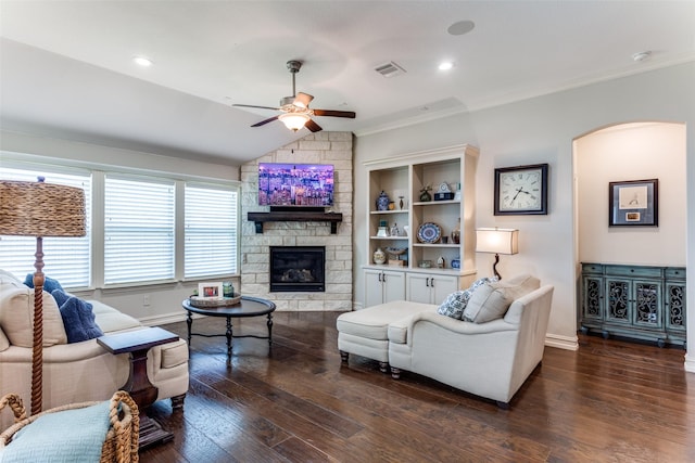 living room featuring dark wood-type flooring, lofted ceiling, a stone fireplace, ornamental molding, and ceiling fan