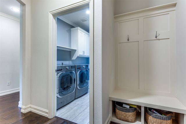 clothes washing area with cabinets, crown molding, washer and dryer, and dark hardwood / wood-style floors