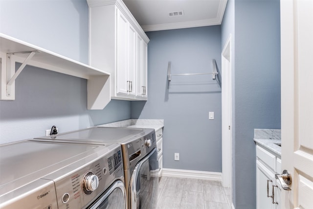 clothes washing area featuring crown molding, cabinets, and washing machine and clothes dryer