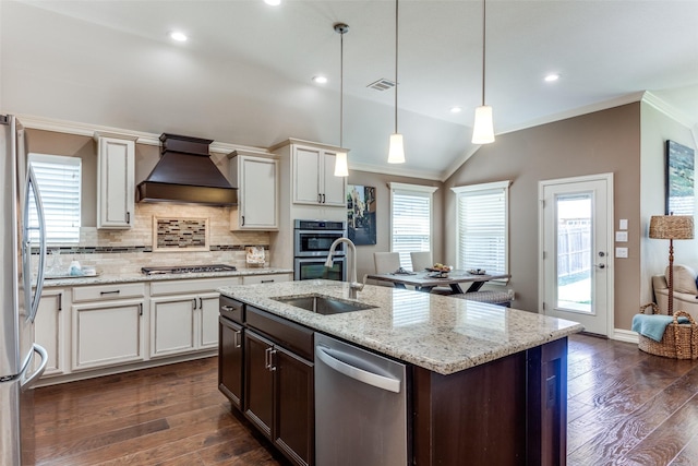 kitchen featuring sink, custom exhaust hood, vaulted ceiling, hanging light fixtures, and stainless steel appliances