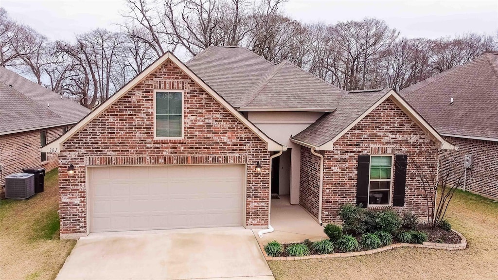 view of front property featuring a garage, cooling unit, and a front lawn