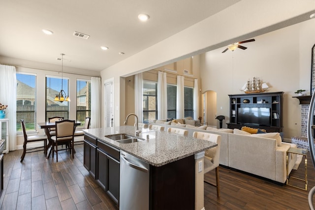 kitchen featuring pendant lighting, sink, light stone countertops, an island with sink, and stainless steel dishwasher