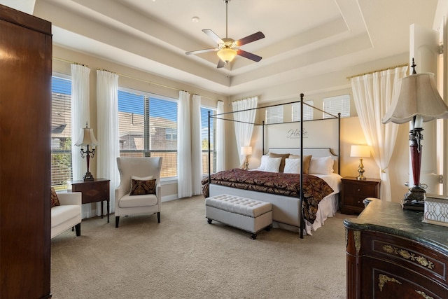 carpeted bedroom featuring a tray ceiling and ceiling fan