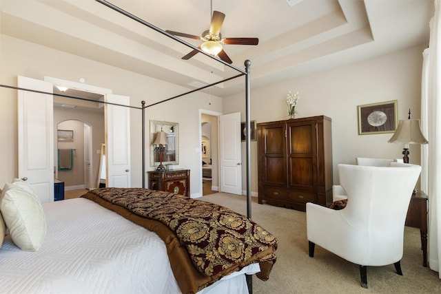 bedroom with a tray ceiling, light colored carpet, and ceiling fan