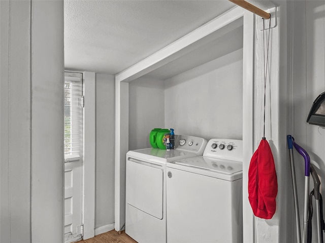 washroom featuring light hardwood / wood-style floors, washer and dryer, and a textured ceiling