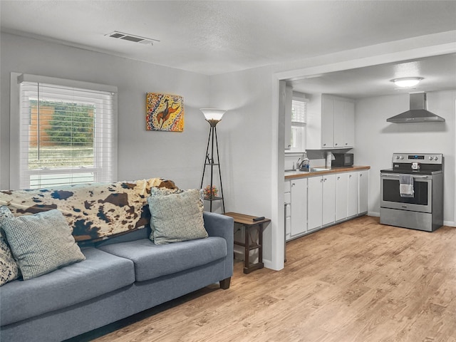 living room featuring light wood-type flooring, sink, a textured ceiling, and a wealth of natural light