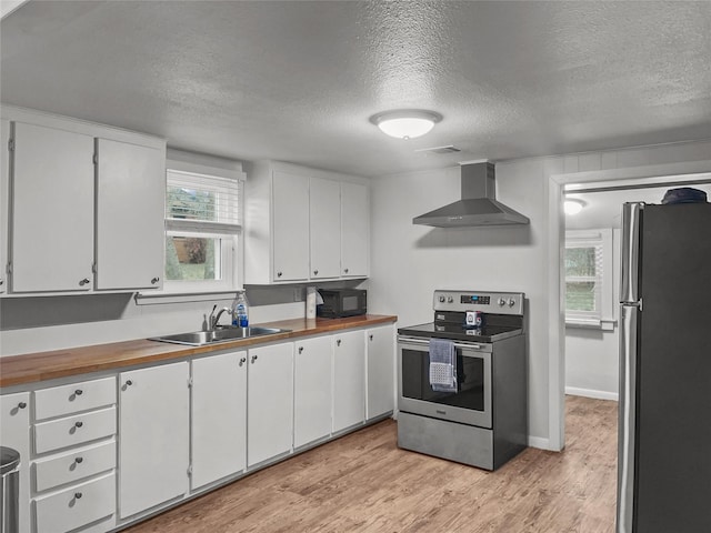 kitchen with white cabinetry, stainless steel appliances, and wall chimney exhaust hood