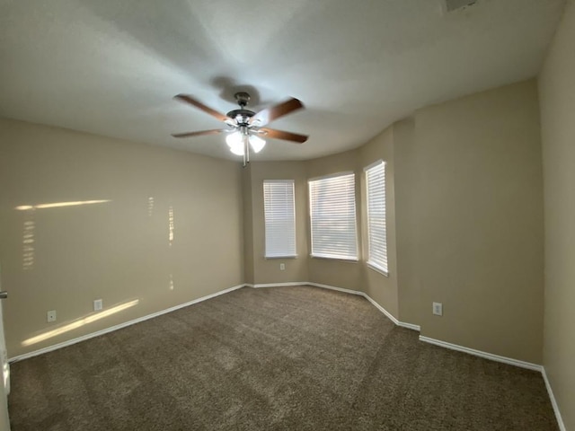 empty room with ceiling fan and dark colored carpet