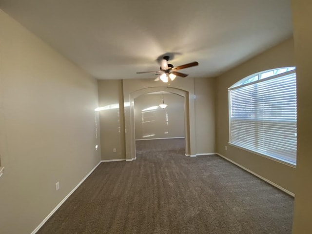 spare room with ceiling fan and dark carpet