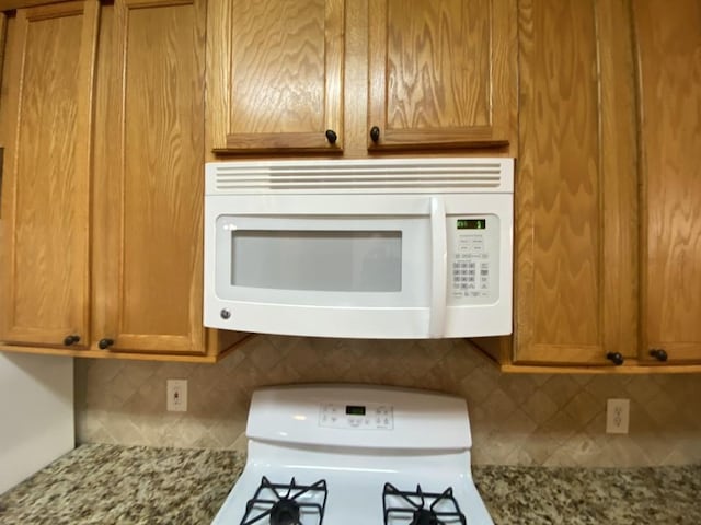 details featuring white appliances, light stone countertops, and decorative backsplash