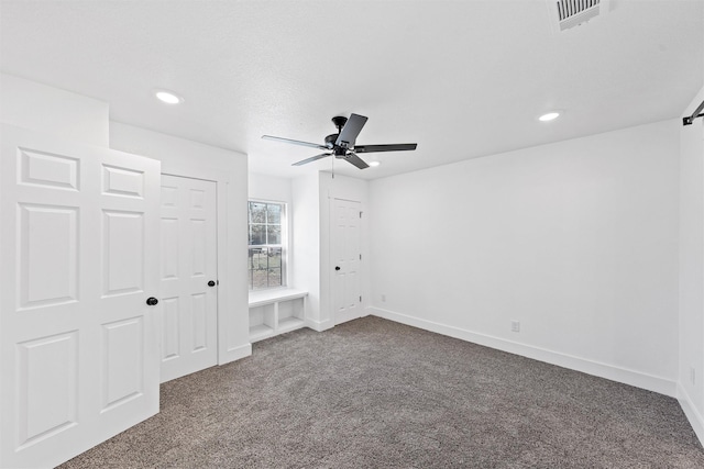 unfurnished bedroom with dark colored carpet and ceiling fan