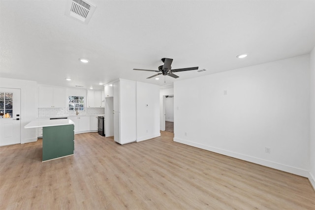 unfurnished living room featuring sink, light hardwood / wood-style flooring, and ceiling fan