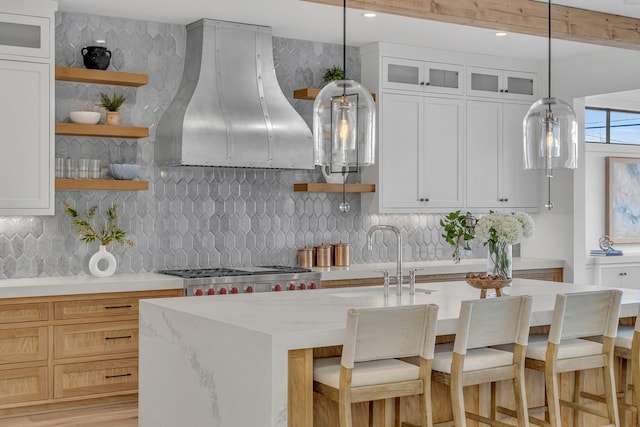 kitchen with white cabinetry, decorative light fixtures, ventilation hood, and tasteful backsplash