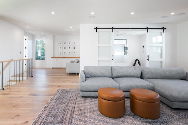 living room with a barn door and light wood-type flooring