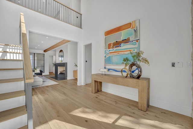 entrance foyer featuring beam ceiling, a towering ceiling, and light wood-type flooring