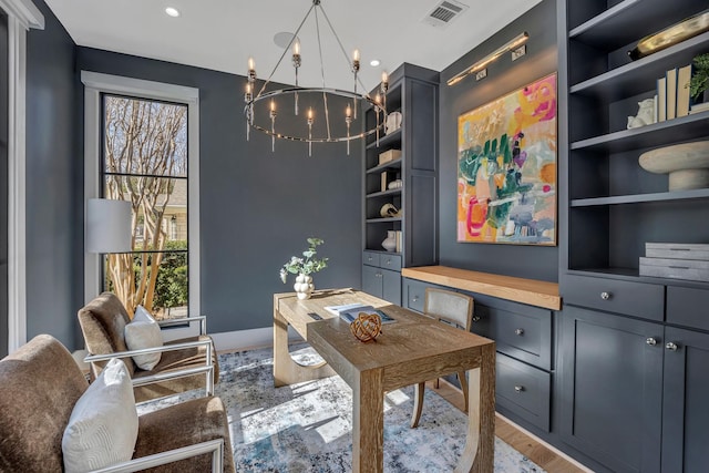 office space featuring wood-type flooring, built in features, and a chandelier