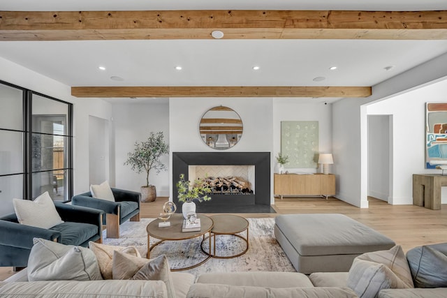 living room featuring beamed ceiling and light hardwood / wood-style floors