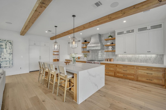 kitchen featuring beam ceiling, exhaust hood, white cabinets, a large island, and backsplash