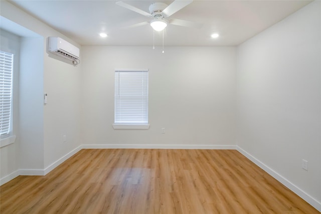 spare room with light hardwood / wood-style flooring, a wall unit AC, and ceiling fan