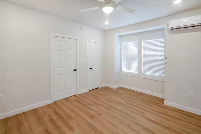 unfurnished room with a wall mounted AC, ceiling fan, and light hardwood / wood-style flooring