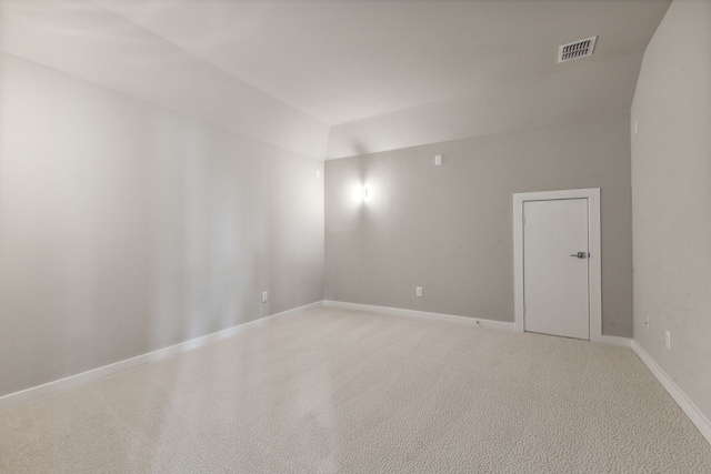 carpeted empty room featuring vaulted ceiling