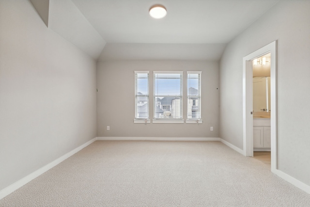 carpeted spare room featuring vaulted ceiling