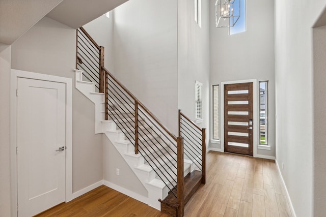 foyer with a towering ceiling, a notable chandelier, and light hardwood / wood-style floors