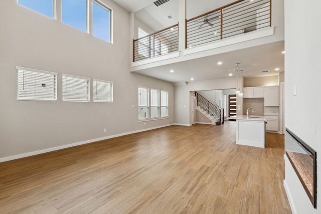 unfurnished living room featuring a towering ceiling and light hardwood / wood-style flooring