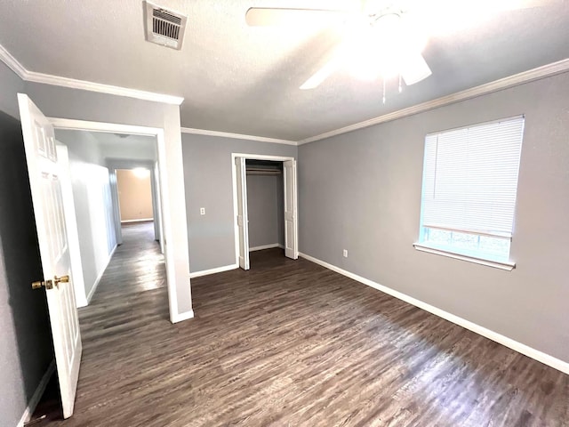 unfurnished bedroom with a textured ceiling, ornamental molding, dark hardwood / wood-style floors, a closet, and ceiling fan