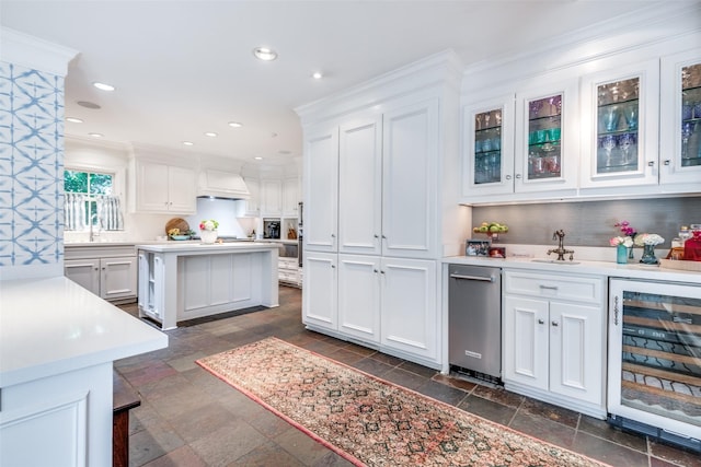 kitchen featuring wine cooler, sink, custom exhaust hood, a center island, and white cabinets