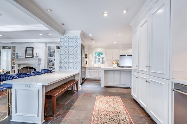 kitchen with white cabinetry, a kitchen island, a breakfast bar, and crown molding